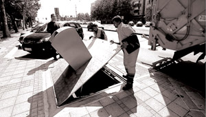 The container lid is raised vertically, which allows the truck crane to access the plastic container.