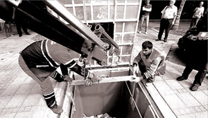 The worker hangs the handle of the plastic container to the crane hook.