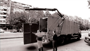 The crane puts down the plastic container to the truck.
