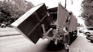 The crane puts down the plastic container to the truck.